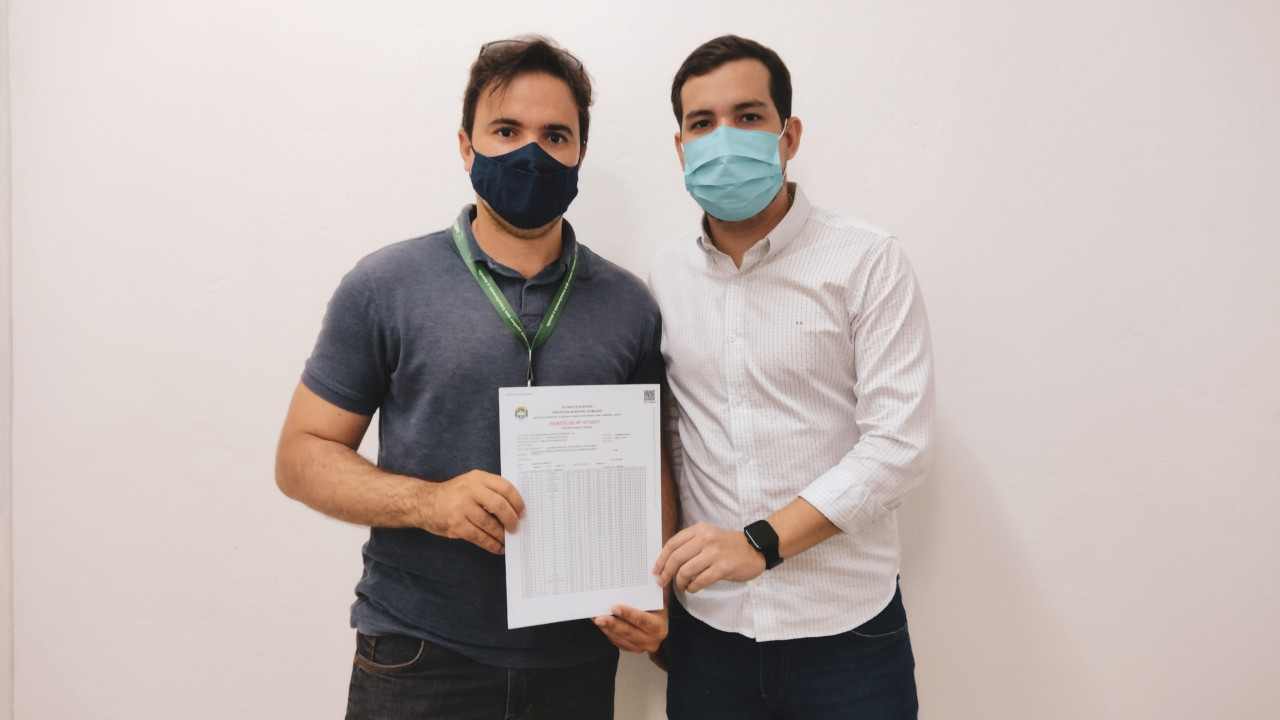 Assessor Leandro Costa (branco) entregando o habite-se ao engenheiro civil da MRV. Foto: Ascom Sedet