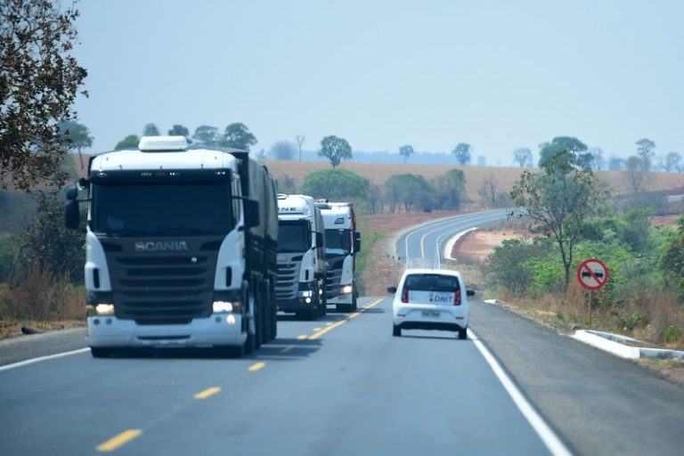 Caminhões e carros numa estrada de dia