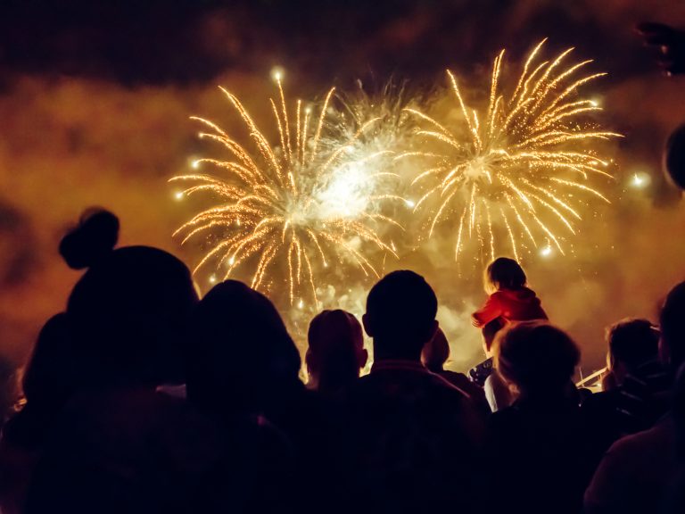 Sombra de pessoas de costas vendo a queima de fogos de artifício no céu escuro