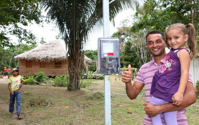 Homem com criança no colo em frente a poste em fazenda