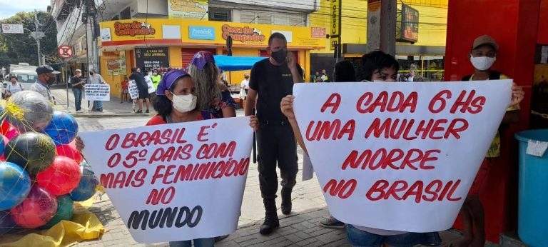 Pessoas na rua protestando contra o feminicídio. Elas seguram uma faixa onde se lê: A cada 6hs uma mulher morre no Brasil