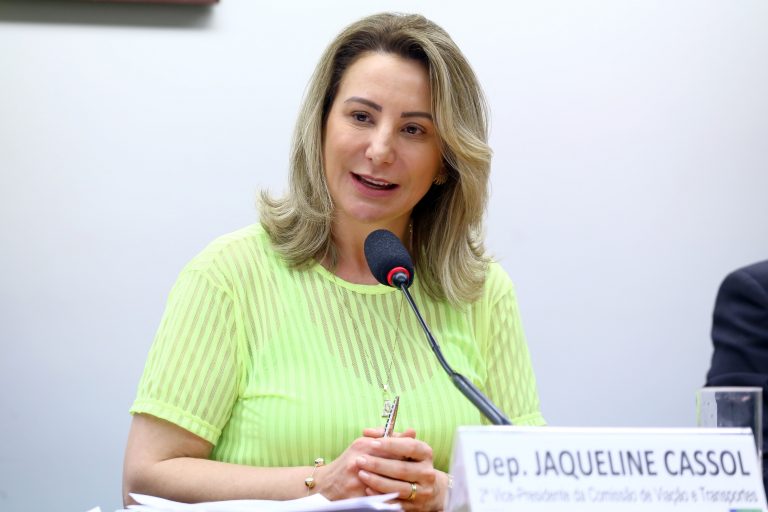 Deputada Jaqueline Cassol está sentada falando ao microfone