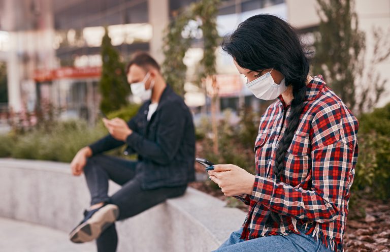 Tecnologia - geral - telefone celular - máscara facial - covid-19 - pandemia - Mulher de máscara usando smartphone
