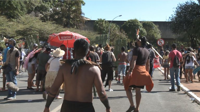 ìndios enfrentam policiais em frente a um prédio baixo