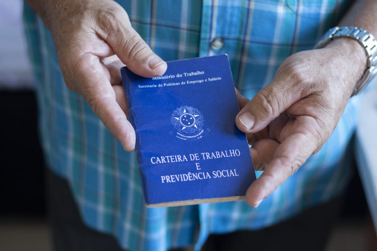 Um homem segura uma carteira de trabalho