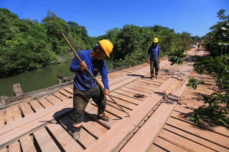 Operários trabalham na construção de uma ponte sobre um rio