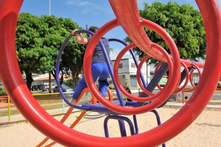 Uma criança desce num escorregador num parquinho de areia. e