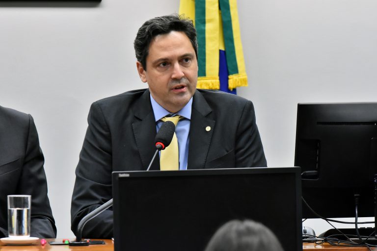 Deputado Luiz Philippe de Orleanse Bragança está sentado falando ao microfone. Ele é branco, tem cabelo escuro e usa um terno preto