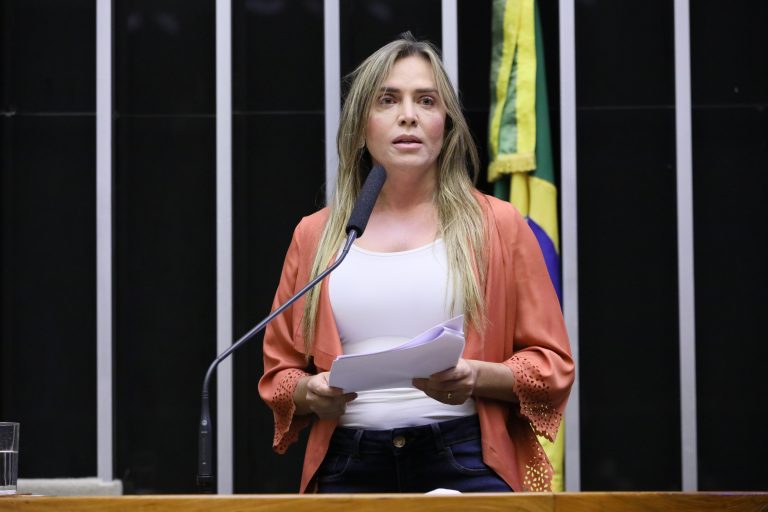 Deputada Celina Leão discursa no Plenário da Câmara. Ela é loira e veste uma camisa branca e um casaco laranja