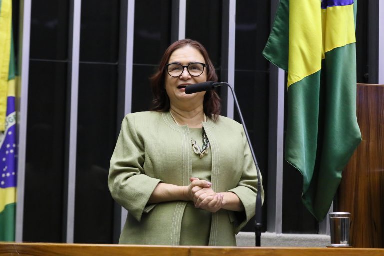 Deputada Professora Rosa Neide discursa no Plenário da Câmara. Ela veste um casaco cáqui e usa óculos