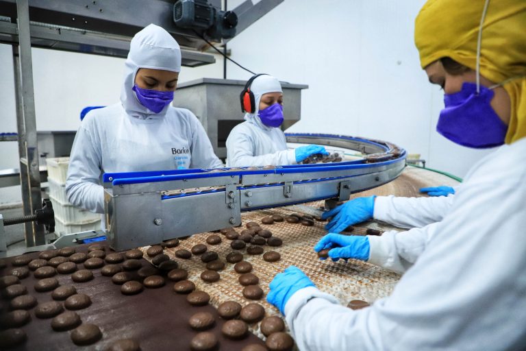 Pessoas trabalham numa fábrica de biscoito