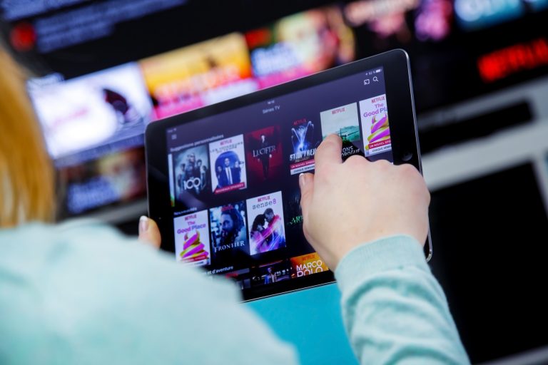 Mulher olha tablet com opção de filmes em streaming