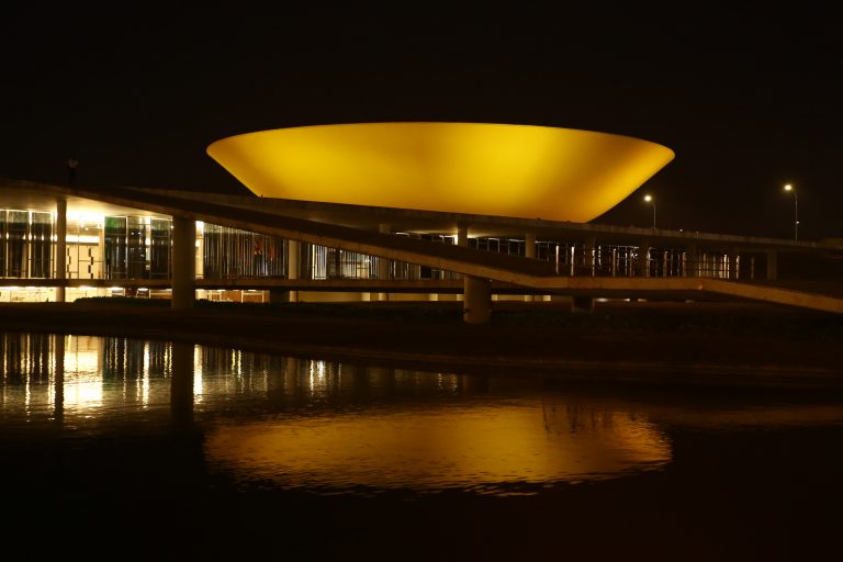 Prédio do Congresso iluminado de amarelo. Ao fundo a noite escura