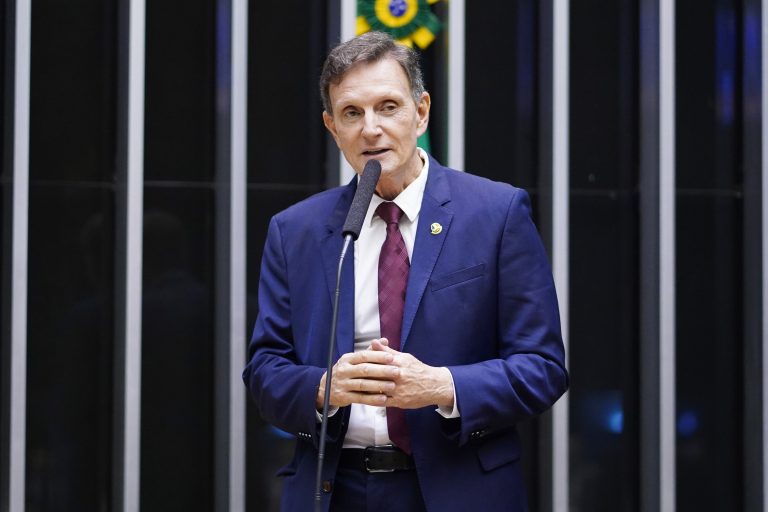 Deputado Marcelo Crivella fala ao microfone. Ele é um homem branco com cabelo castanho claro, usa terno azul-marinho e camisa branca