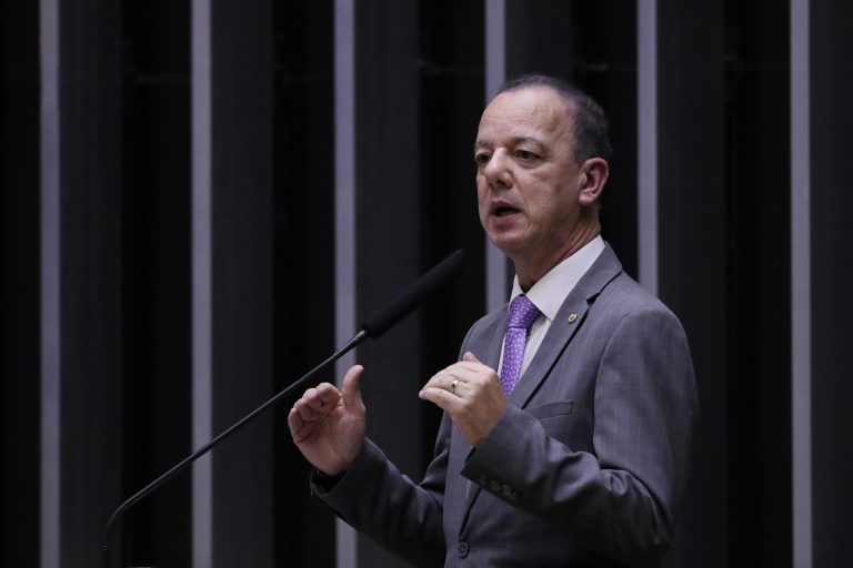 Deputado Ismael fala ao microfone. Ele é um homem branco, tem o cabelo escuro e veste terno cinza